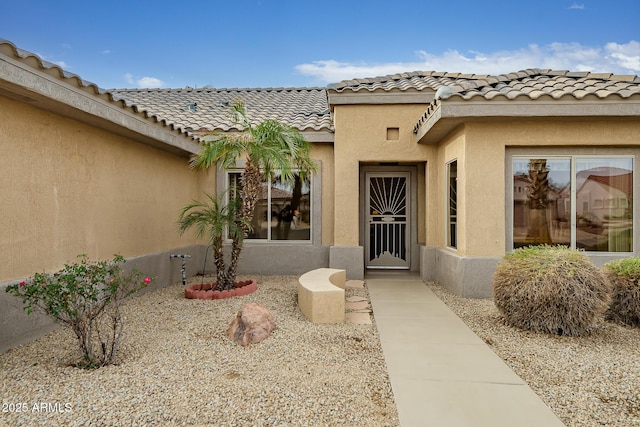 entrance to property with a tile roof and stucco siding