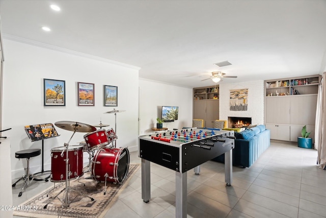 playroom with light tile floors, brick wall, ceiling fan, and a fireplace