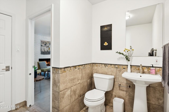 bathroom featuring tile walls, toilet, and tile flooring