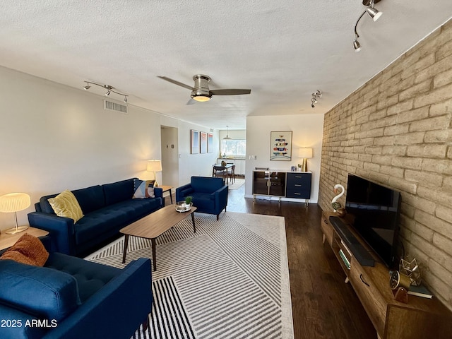 living room featuring a ceiling fan, wood finished floors, a textured ceiling, rail lighting, and visible vents