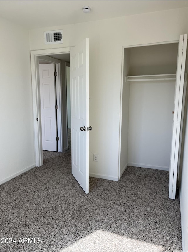 unfurnished bedroom featuring a closet and dark carpet