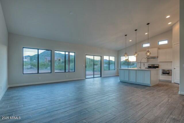 kitchen featuring pendant lighting, a center island with sink, white cabinets, and light hardwood / wood-style flooring