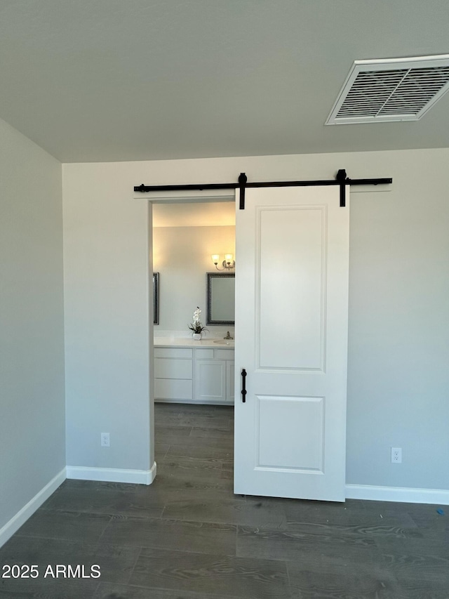 spare room with dark hardwood / wood-style floors and a barn door