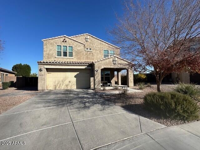 mediterranean / spanish-style house featuring an attached garage, a tile roof, concrete driveway, and stucco siding