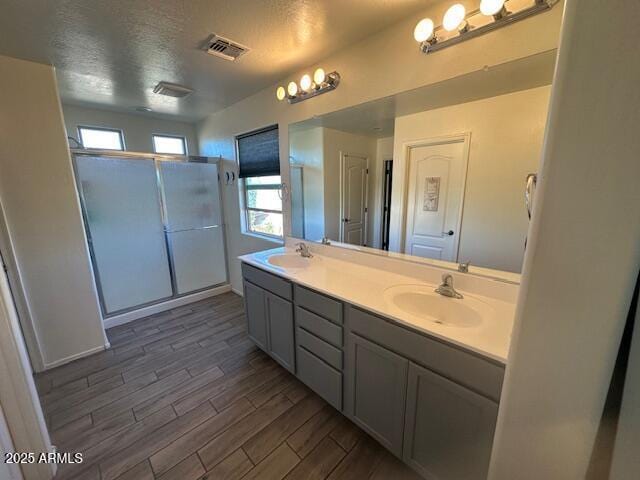 bathroom with vanity, hardwood / wood-style floors, a textured ceiling, and walk in shower