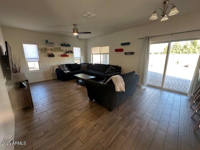 living room with ceiling fan with notable chandelier, dark hardwood / wood-style floors, and a wealth of natural light