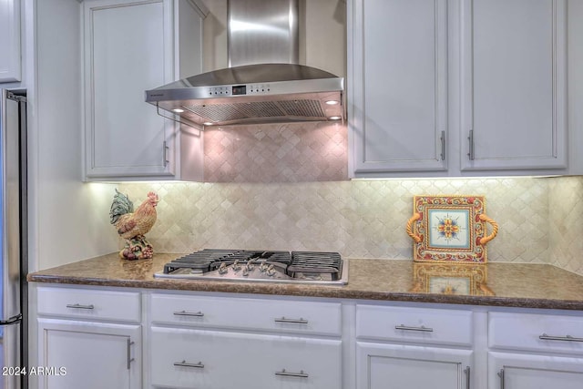 kitchen with stainless steel appliances, wall chimney range hood, white cabinetry, and decorative backsplash