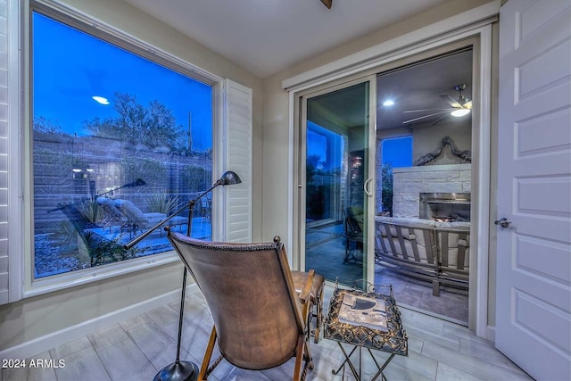 sitting room with a ceiling fan, a fireplace, and baseboards