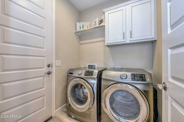 clothes washing area featuring light tile patterned flooring, cabinet space, baseboards, and separate washer and dryer