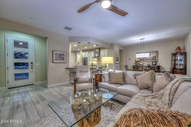 living room with ceiling fan, baseboards, visible vents, and wood tiled floor
