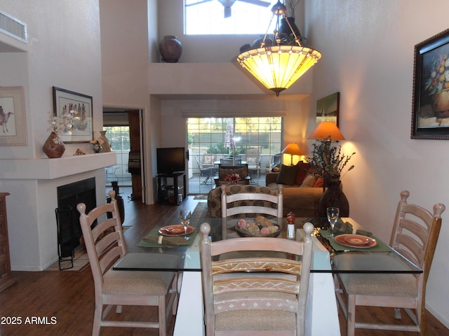 dining room with a fireplace with flush hearth, wood finished floors, visible vents, and a healthy amount of sunlight