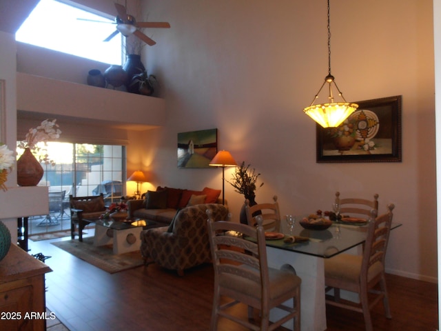 dining space with a high ceiling, a ceiling fan, and wood finished floors