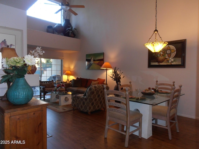 dining space with wood finished floors, a towering ceiling, and ceiling fan