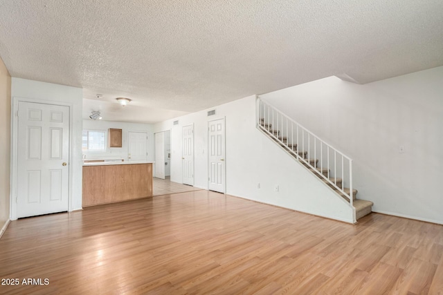 18239 N 40th St Unit 122, Phoenix, AZ 85032 - unfurnished living room featuring light wood-type flooring, a textured ceiling, and stairs