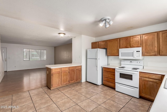 18239 N 40th St Unit 122, Phoenix, AZ 85032 - kitchen with white appliances, a peninsula, light countertops, brown cabinetry, and a textured ceiling
