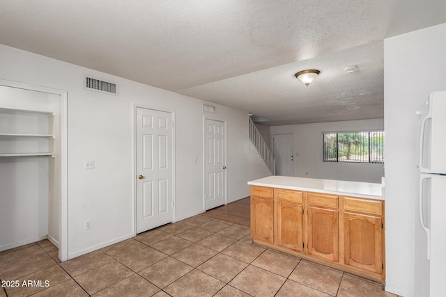 18239 N 40th St Unit 122, Phoenix, AZ 85032 - kitchen with freestanding refrigerator, a textured ceiling, light countertops, and light tile patterned floors