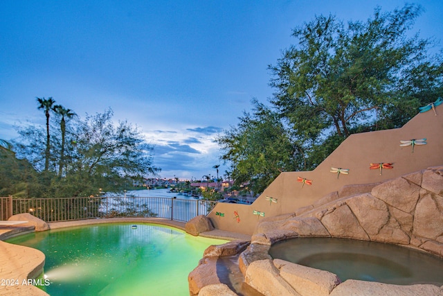 view of swimming pool with an in ground hot tub and a water view