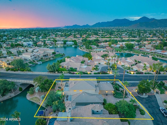 aerial view at dusk featuring a water and mountain view