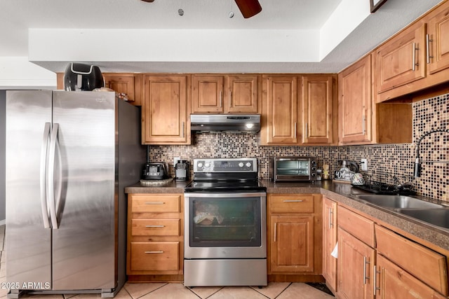 617 E Calle Adobe Ln, Goodyear, AZ 85338 - kitchen with stainless steel appliances, under cabinet range hood, light tile patterned floors, and decorative backsplash