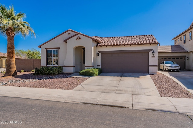 mediterranean / spanish house with stucco siding, an attached garage, concrete driveway, and fence