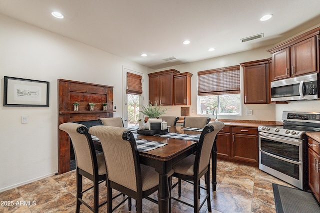 dining room featuring stone finish floor, recessed lighting, and visible vents