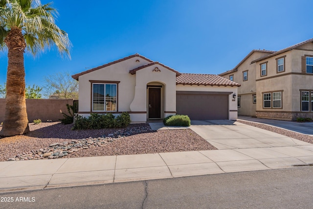 mediterranean / spanish-style home with an attached garage, fence, a tiled roof, stucco siding, and driveway