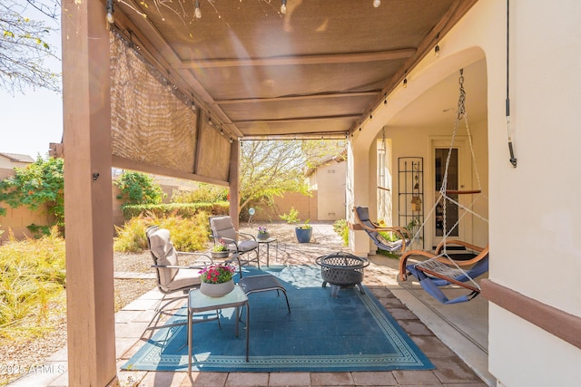 view of patio featuring an outdoor fire pit and fence