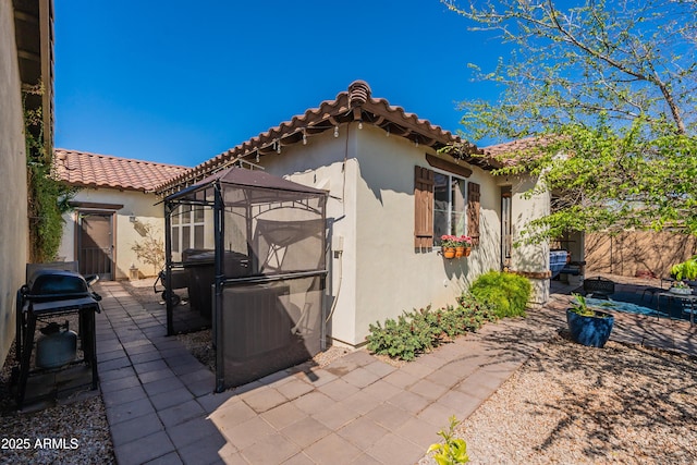 exterior space with a tiled roof, stucco siding, and a patio area