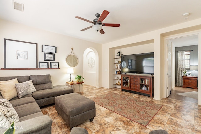 living room with arched walkways, visible vents, and a ceiling fan