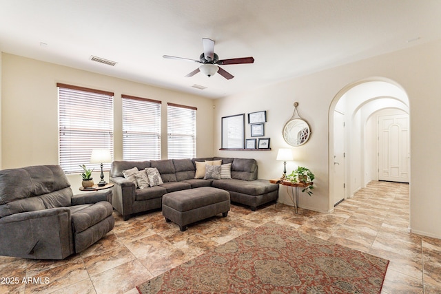 living area with arched walkways, visible vents, and a ceiling fan