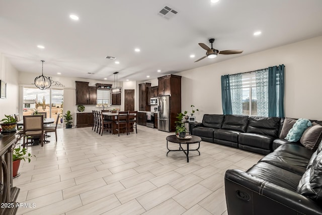 living area with recessed lighting, visible vents, and ceiling fan with notable chandelier