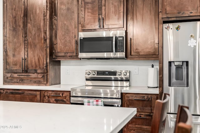 kitchen featuring stainless steel appliances, dark brown cabinetry, and light countertops