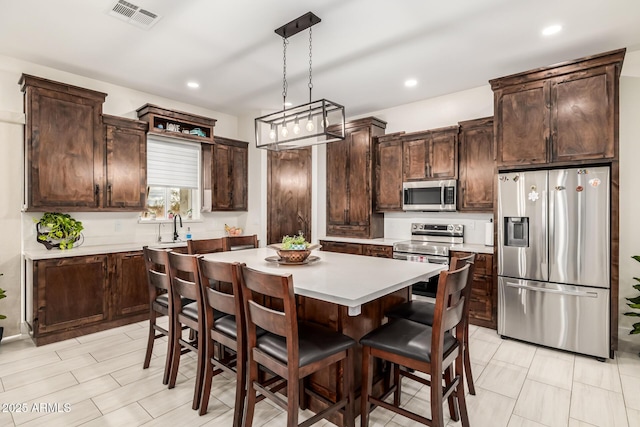 kitchen with dark brown cabinets, appliances with stainless steel finishes, a center island, and light countertops