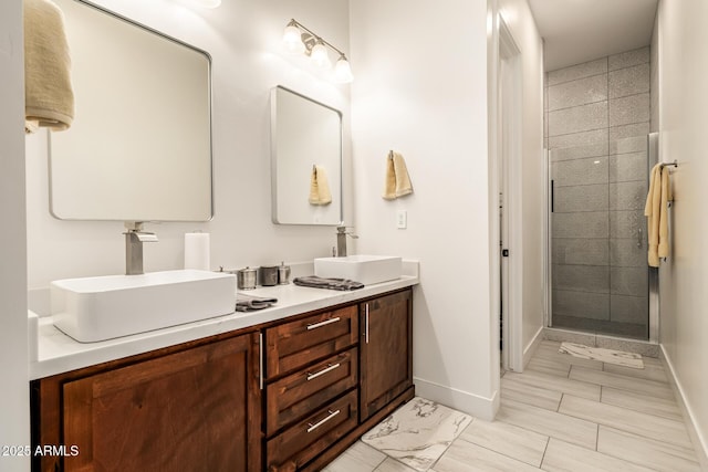 bathroom with double vanity, baseboards, a stall shower, and a sink