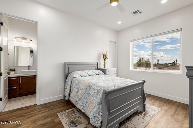 bedroom featuring baseboards, light wood-style floors, visible vents, and a sink