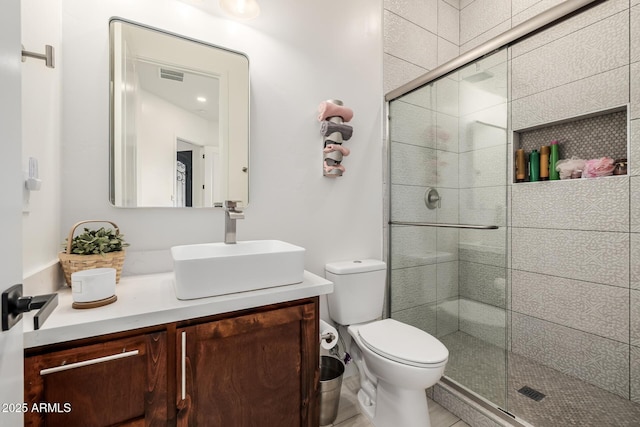 bathroom with visible vents, vanity, toilet, and a shower stall