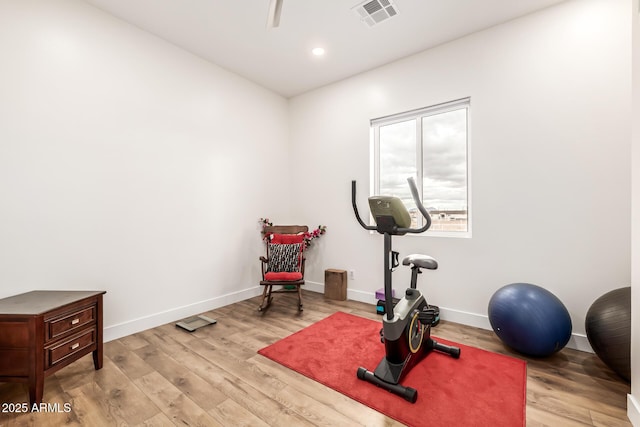 exercise room featuring baseboards, visible vents, and light wood finished floors