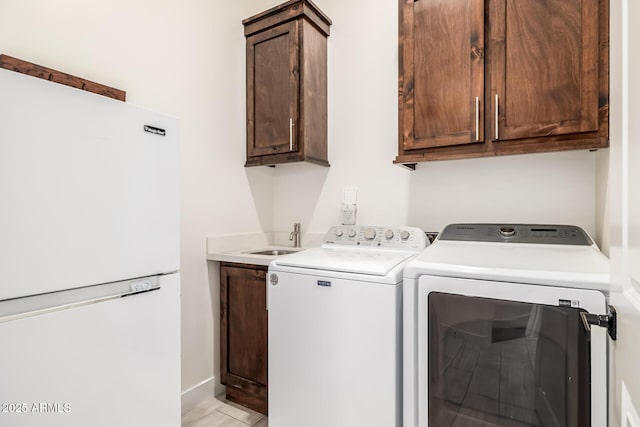 clothes washing area featuring a sink, baseboards, cabinet space, and washing machine and clothes dryer