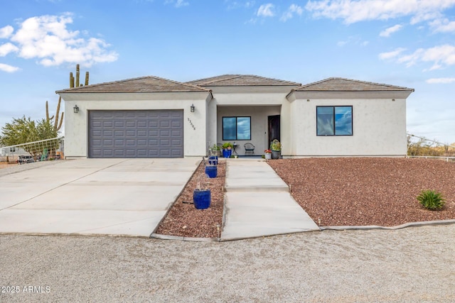 view of front of house featuring fence, a garage, driveway, and stucco siding