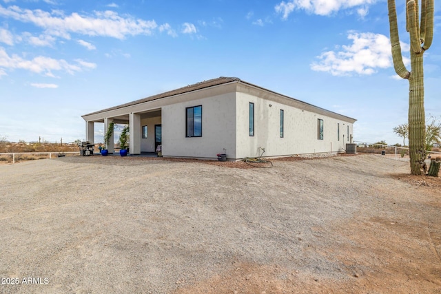 view of front of home with central air condition unit, stucco siding, and fence