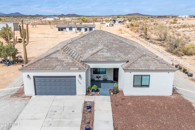 single story home with stucco siding, a mountain view, concrete driveway, and a garage