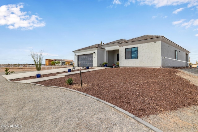 view of front of home featuring a garage, fence, concrete driveway, and stucco siding