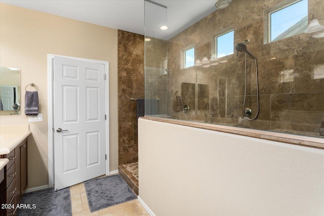 bathroom featuring tiled shower, tile patterned flooring, vanity, and a healthy amount of sunlight