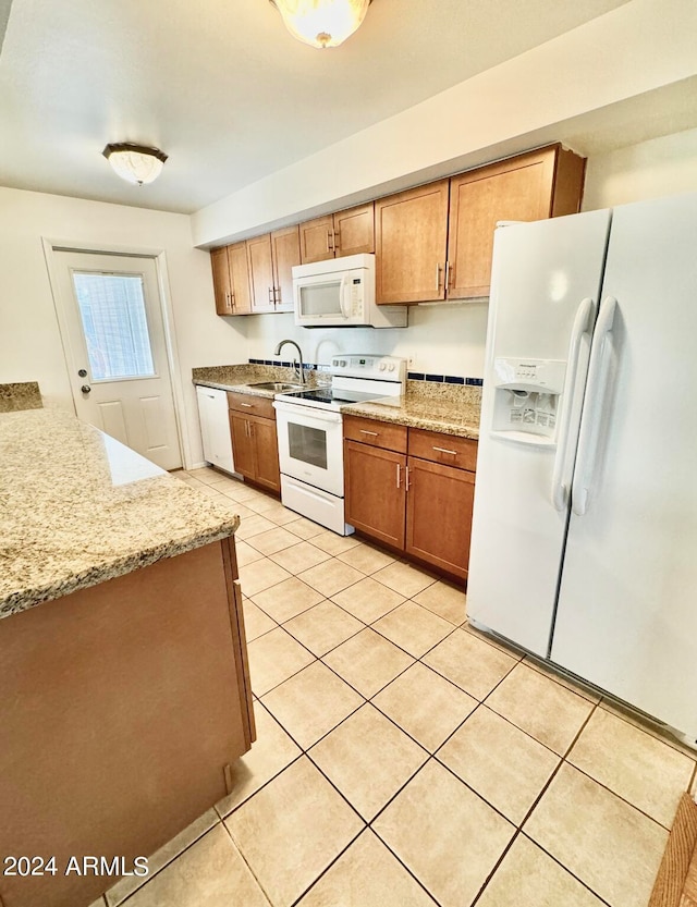 kitchen with light tile patterned flooring, white appliances, light stone countertops, and sink