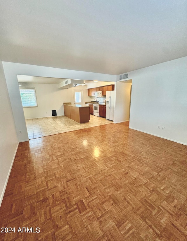 unfurnished living room with light tile patterned flooring and a wealth of natural light