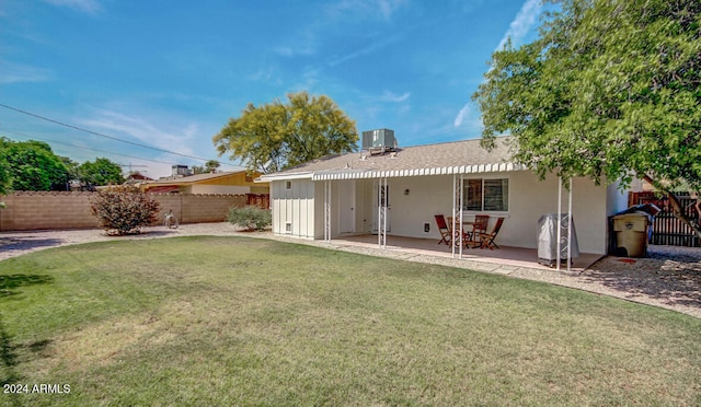 rear view of house with central air condition unit, a patio, and a lawn