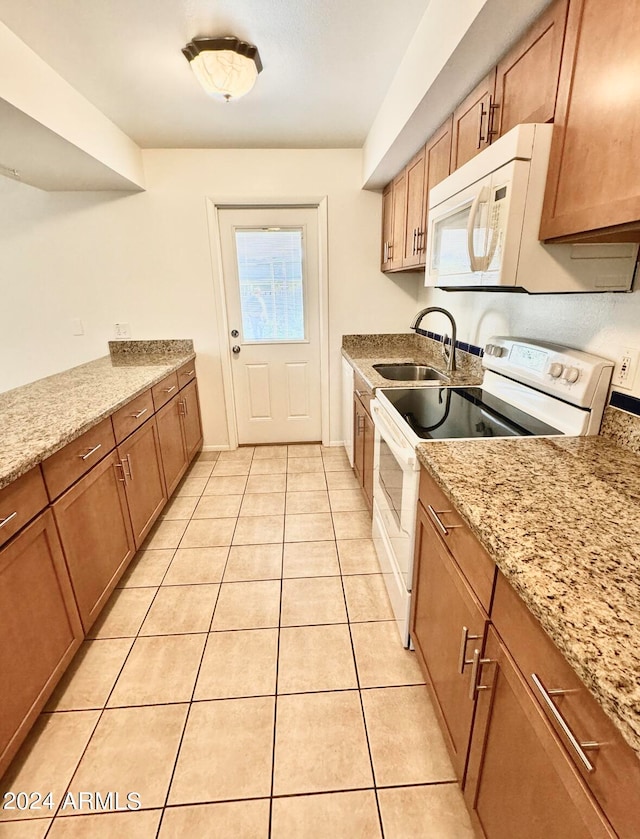 kitchen with light stone counters, light tile patterned flooring, sink, and white appliances