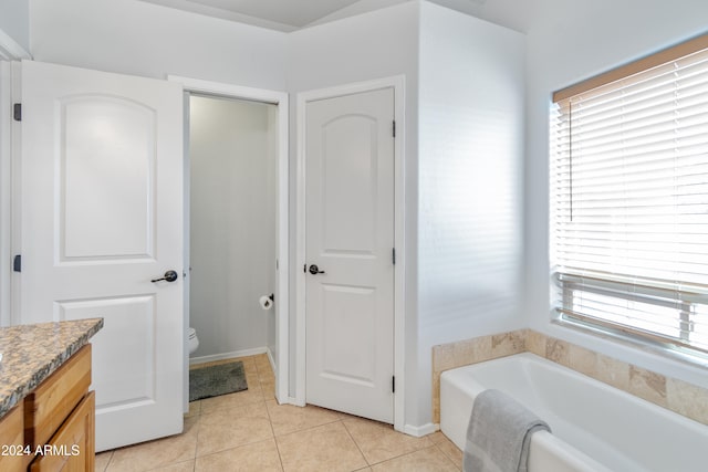 bathroom featuring tile patterned floors, vanity, toilet, and a bath