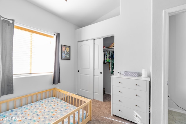 carpeted bedroom featuring a crib, lofted ceiling, and a closet