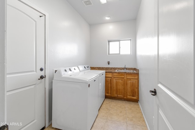 laundry room featuring cabinets, light tile patterned floors, sink, and washing machine and clothes dryer